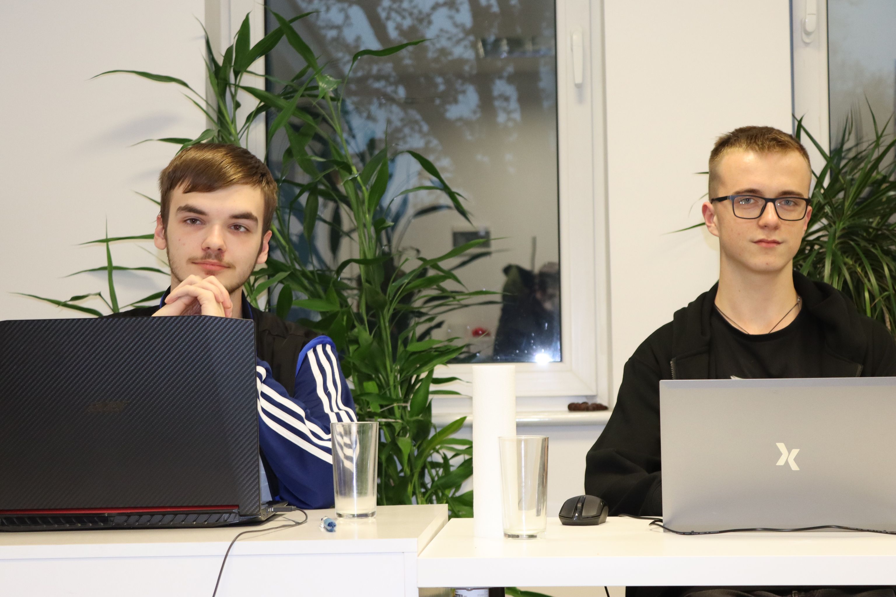 Dwaj młodzi programiści pracujący przy laptopach w biurze